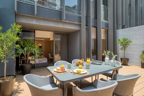 A modern outdoor dining area with a table set for breakfast, surrounded by potted plants and a view of the building's interior. - ULIV Parque Lincoln (Mexico City)