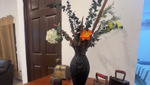 Una mesa de madera con un jarrón de flores, una maleta antigua y dos planchas.