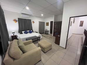 A hotel room with a bed, a sofa, an ottoman, a desk, and a chair. - Hotel Boutique Domenica Isabella's (San Salvador)