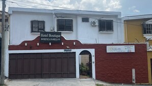 Un edificio de dos plantas con un letrero que dice 'Hotel Boutique Dominicana Isabella's' y un número de contacto.