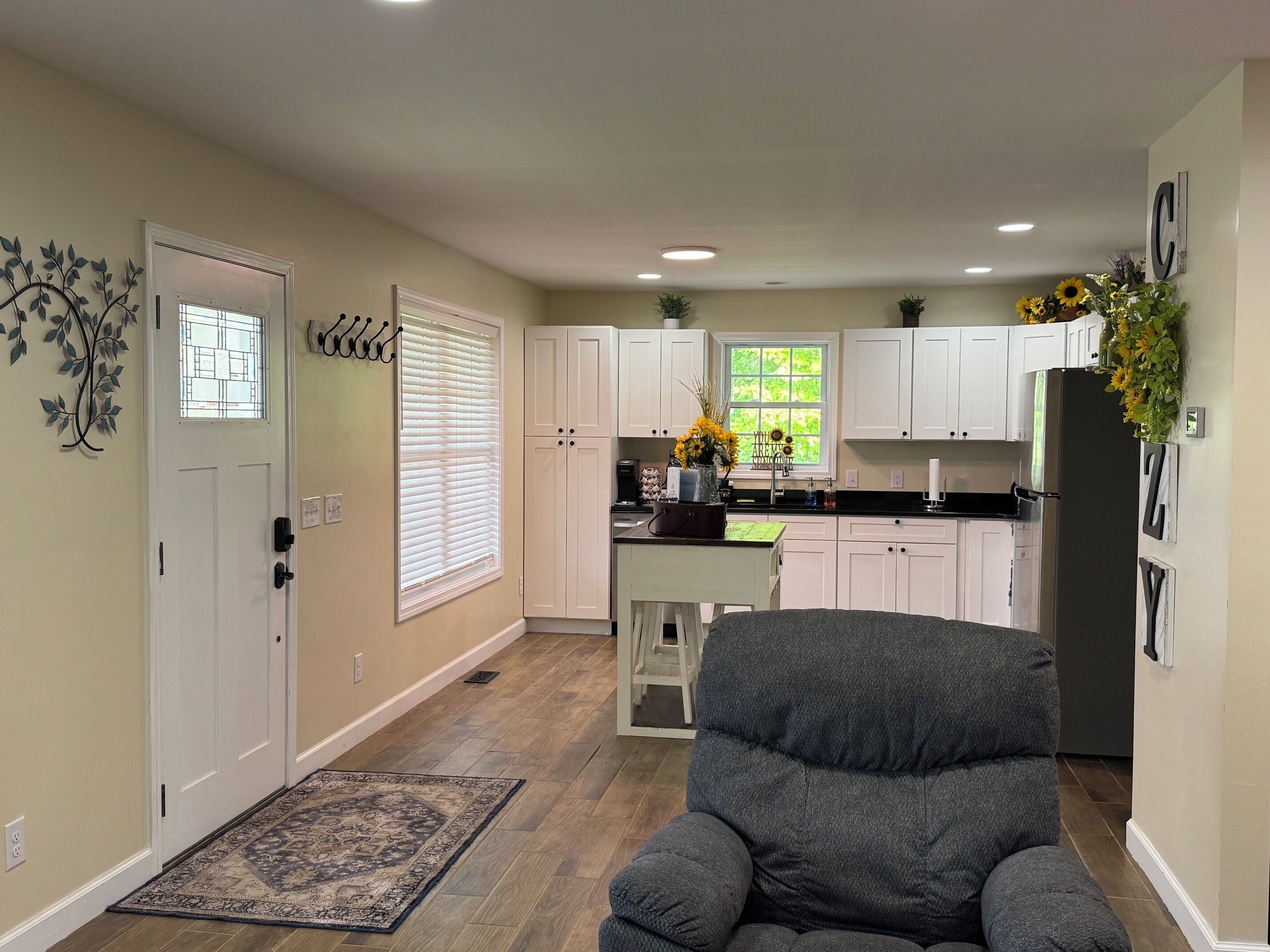 A modern kitchen with white cabinets, a refrigerator, and a window with a view of greenery.