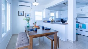 A modern kitchen with white cabinets, a wooden dining table, and a bench.