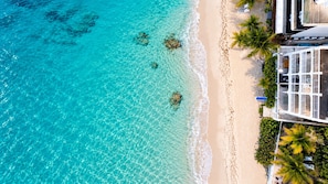 A beachside property with clear turquoise waters, a sandy shore, and a modern building with a balcony overlooking the beach. - 2 BR 2 BA, beachfront condo, amazing oceanview, private beach access (Simpson Bay)