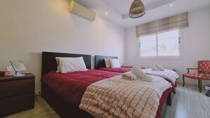 A hotel room with two beds, a desk with a computer, a chair, and a window with curtains. - STAY Serenity Apartment (Engomi)