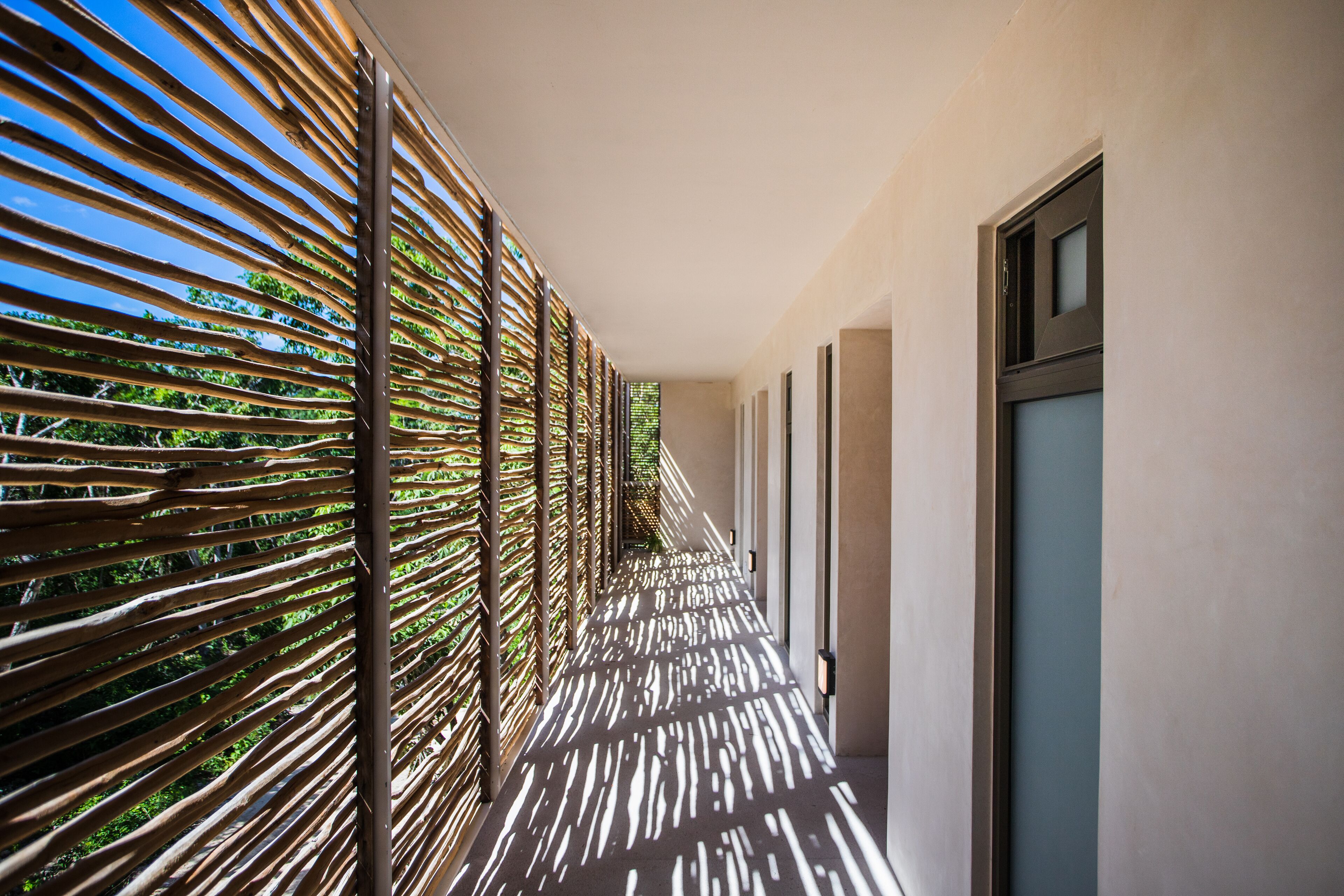 A corridor with a patterned wall and a view of greenery outside.