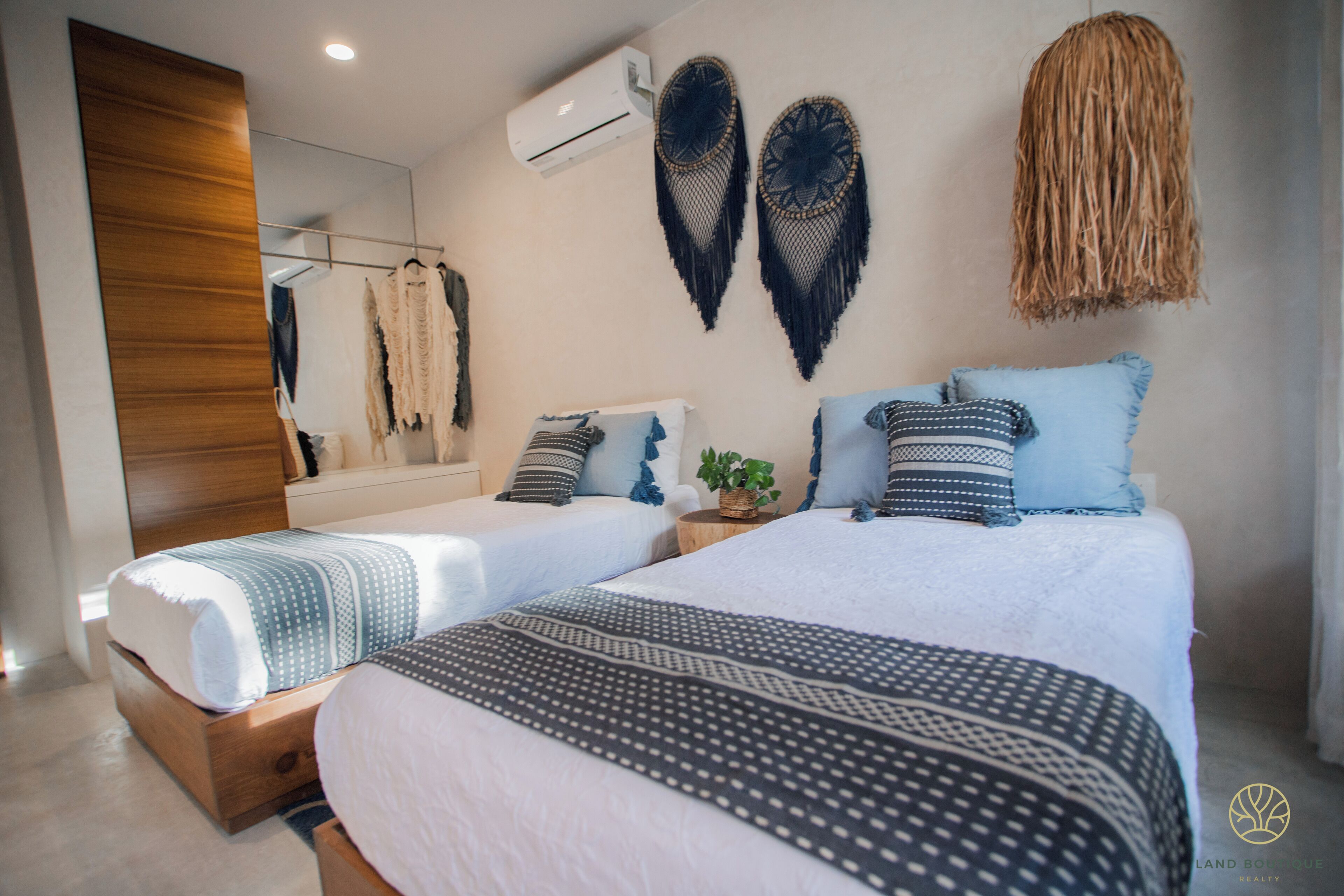 A modern bedroom with two beds, a large mirror, and decorative wall hangings.