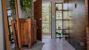A hallway with wooden doors, a mirror, and hanging plants. - Stylish Jungle Studio · Outdoor Tub & Yoga Deck (Tulum)