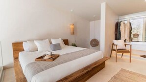 Une chambre moderne avec un lit en bois, une table de chevet, une chaise et une fenêtre où sont suspendus des vêtements.
