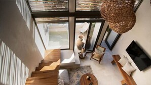 Un intérieur moderne avec un escalier, un coin salon et une grande fenêtre.
