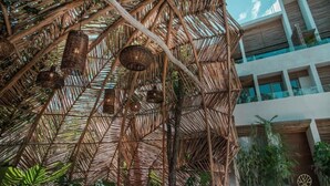 Un bâtiment moderne à la structure en bambou, agrémenté de suspensions florales.