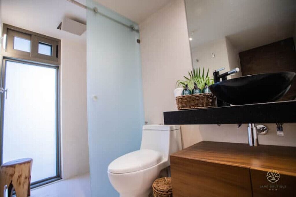 Une salle de bain moderne avec des toilettes, un meuble-lavabo en bois et un lavabo noir.