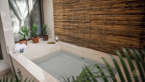 Un bagno con vasca, piante in vaso e parete in bambù.