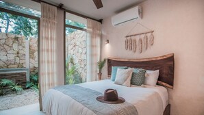 Una camera da letto con un letto grande, un muro in pietra e vista sul verde.