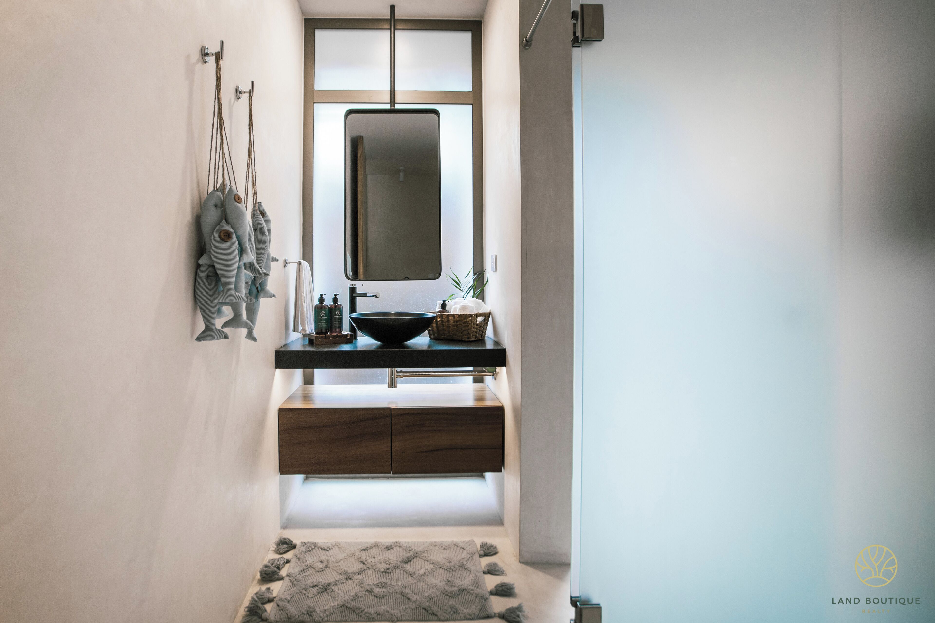 Une salle de bain moderne avec un grand miroir, un meuble-lavabo en bois et un petit tapis sur le sol.