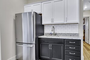 Enjoy cooking in this well-equipped kitchen with a refrigerator, black cabinetry, and granite countertop.
