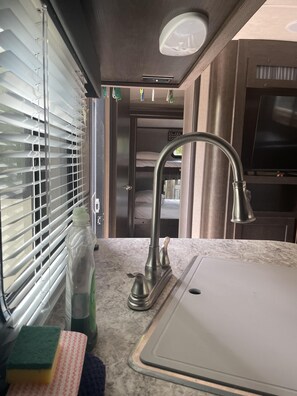 A compact kitchen with a sink, faucet, and window blinds.