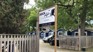 Et træskilt med kontaktoplysninger for Dock X Cottages.