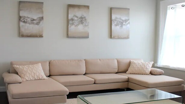 A living room with a beige sectional sofa, a glass coffee table, and three abstract wall art pieces. - ★MODERN 1BR GREAT Location Downtown! W/D Parking!★ (Albany)