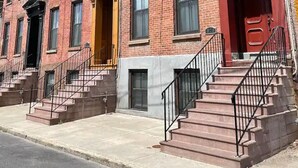 A row of red brick townhouses with multiple windows, a central entrance with a yellow awning, and a red door. - ★MODERN 1BR GREAT Location Downtown! W/D Parking!★ (Albany)