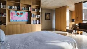 Una camera da letto moderna con un letto grande, scaffali in legno, una scrivania e un quadro.