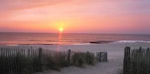 A beach with a wooden fence and sand dunes.