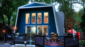 A blue house with a deck, large windows, and a porch area. - Chalet by the Bay Charming Beach Getaway (Lewes)