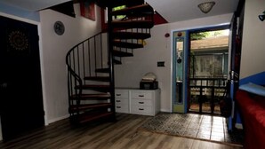 A room with a spiral staircase, a white cabinet, and a red couch. - Chalet by the Bay Charming Beach Getaway (Lewes)