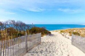 A sandy beach path with a wooden fence on one side and a clear view of the ocean. - Chalet by the Bay Charming Beach Getaway (Lewes)