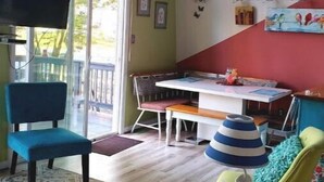 A living room with a TV, a dining table, and chairs. There are butterflies and birds on the wall. - Chalet by the Bay Charming Beach Getaway (Lewes)