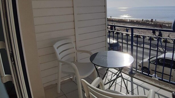 A balcony with a table and chairs, overlooking a beach and a road. - Appartement vue sur mer (Châtelaillon-Plage)