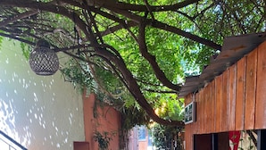 A covered outdoor corridor with tiled flooring, wooden walls, and a staircase with green steps. - Lavinya Pansiyon (Kusadasi)