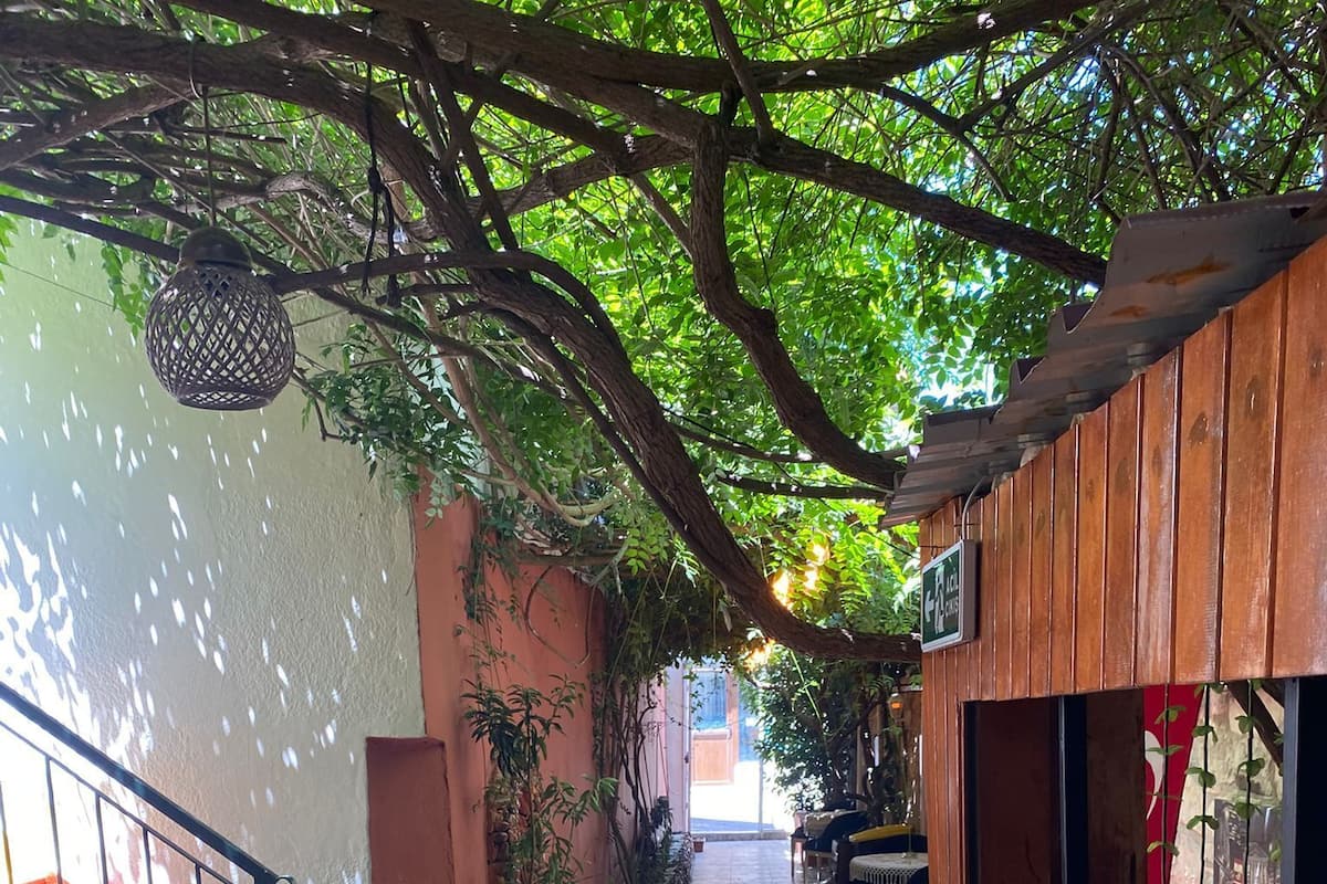 A covered outdoor corridor with tiled flooring, wooden walls, and a staircase with green steps.