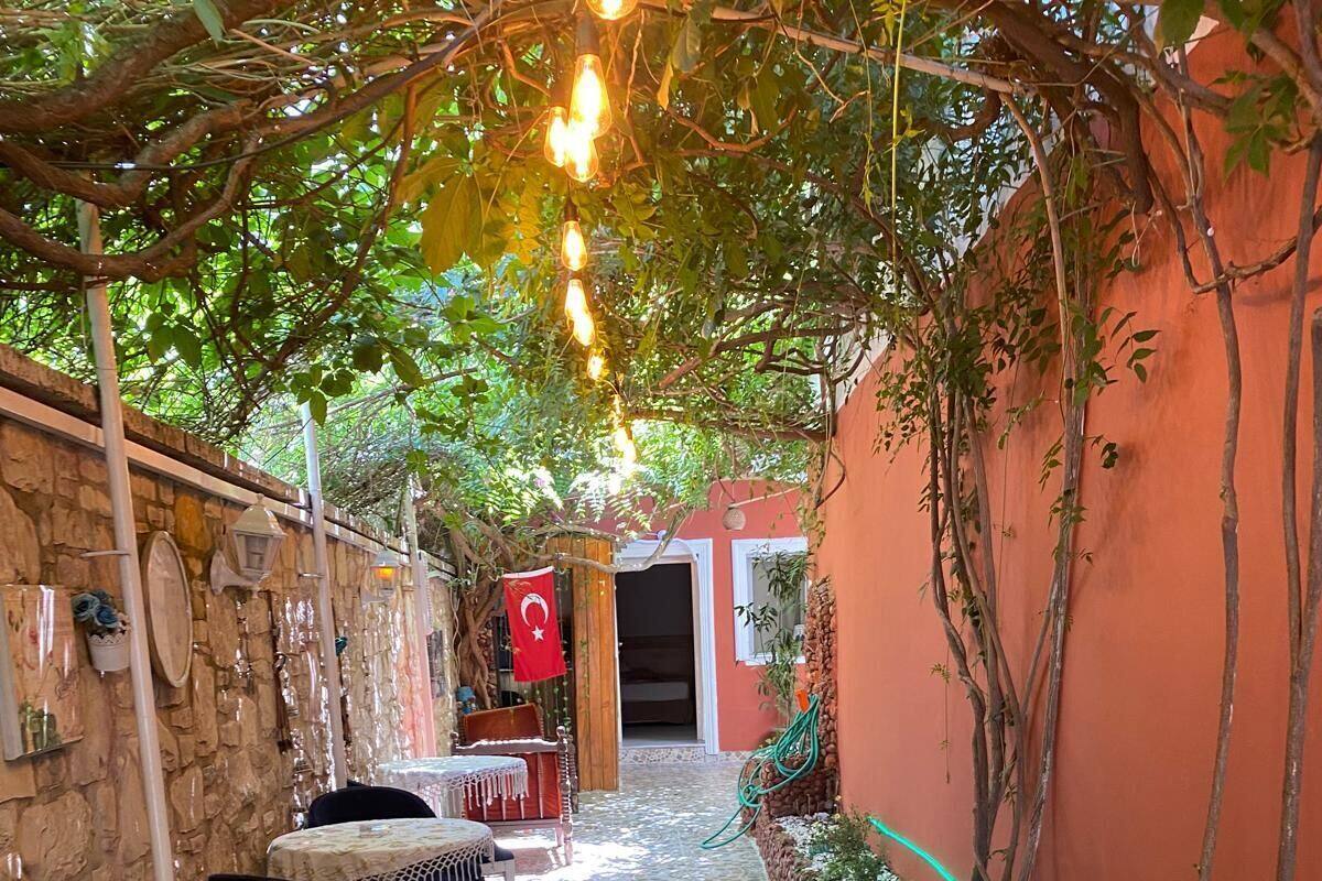 A covered outdoor patio with a mosaic floor, stone walls, and a red wall with a flag.