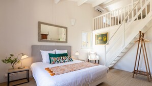 A bedroom with a bed, a nightstand, a lamp, a chair, a wooden ladder, a staircase, and a painting. - 3 bed + villa near Gordes with air-con, pool and stunning views over the Luberon (Cabrières-d'Avignon)