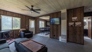 Een moderne woonkamer met een open haard, zithoek en een televisie bevestigd aan een houten wand.