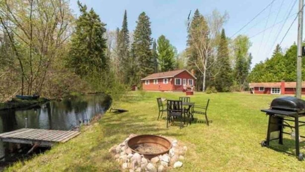 Een vakantiehuis aan het meer met een vuurkuil, tuinmeubels en een barbecue.