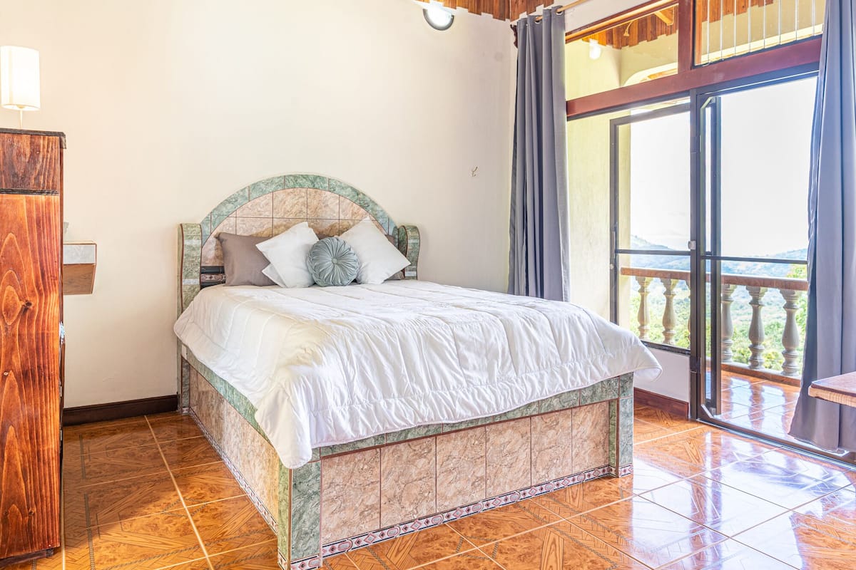 Un dormitorio con cama, un armario de madera y un balcón con vistas.