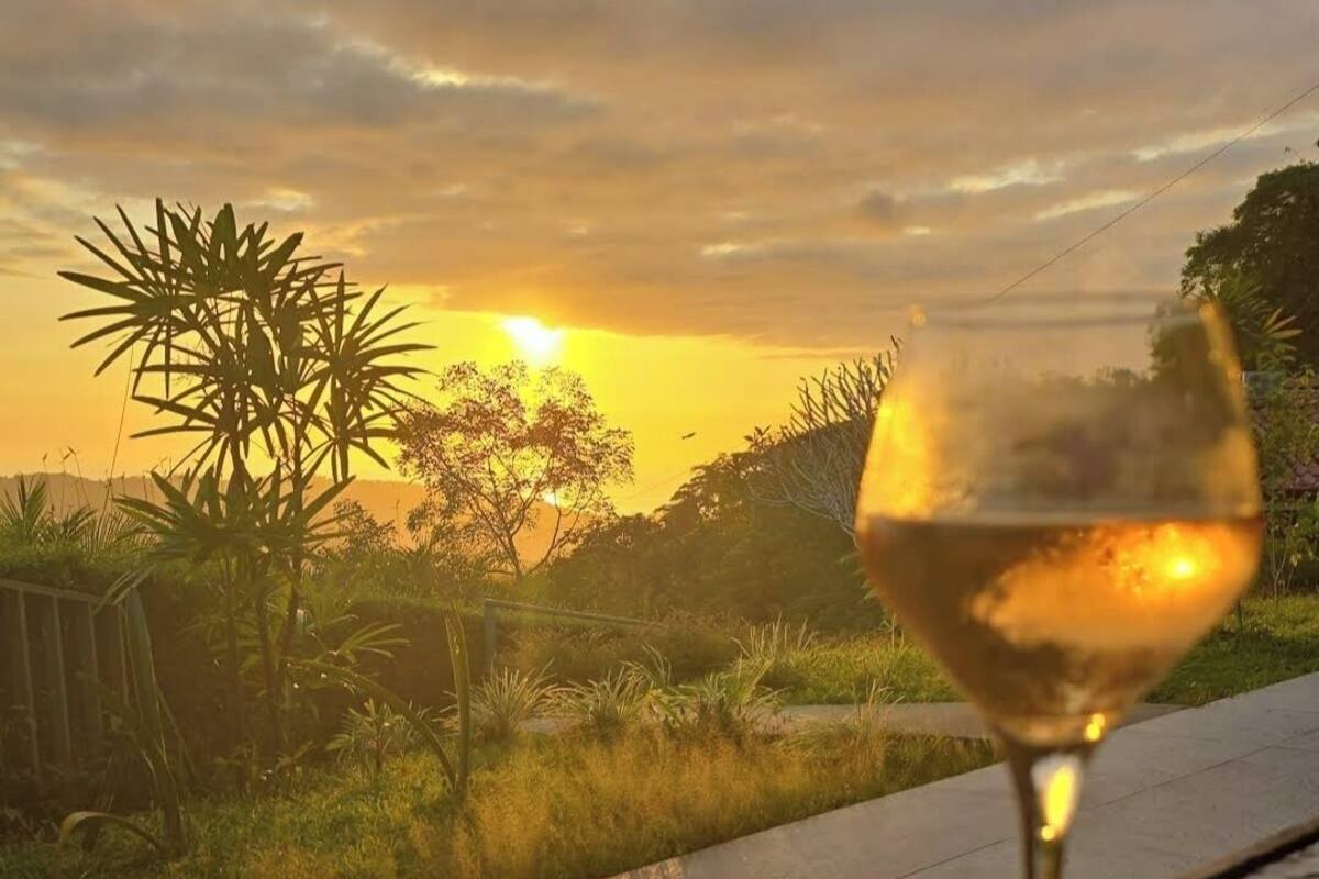 Una copa de vino blanco sobre una mesa con vista al atardecer.