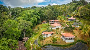 Il s’agit d’une propriété située sur une colline, comprenant plusieurs bâtiments, dont une maison principale avec un toit rouge et plusieurs dépendances plus petites.