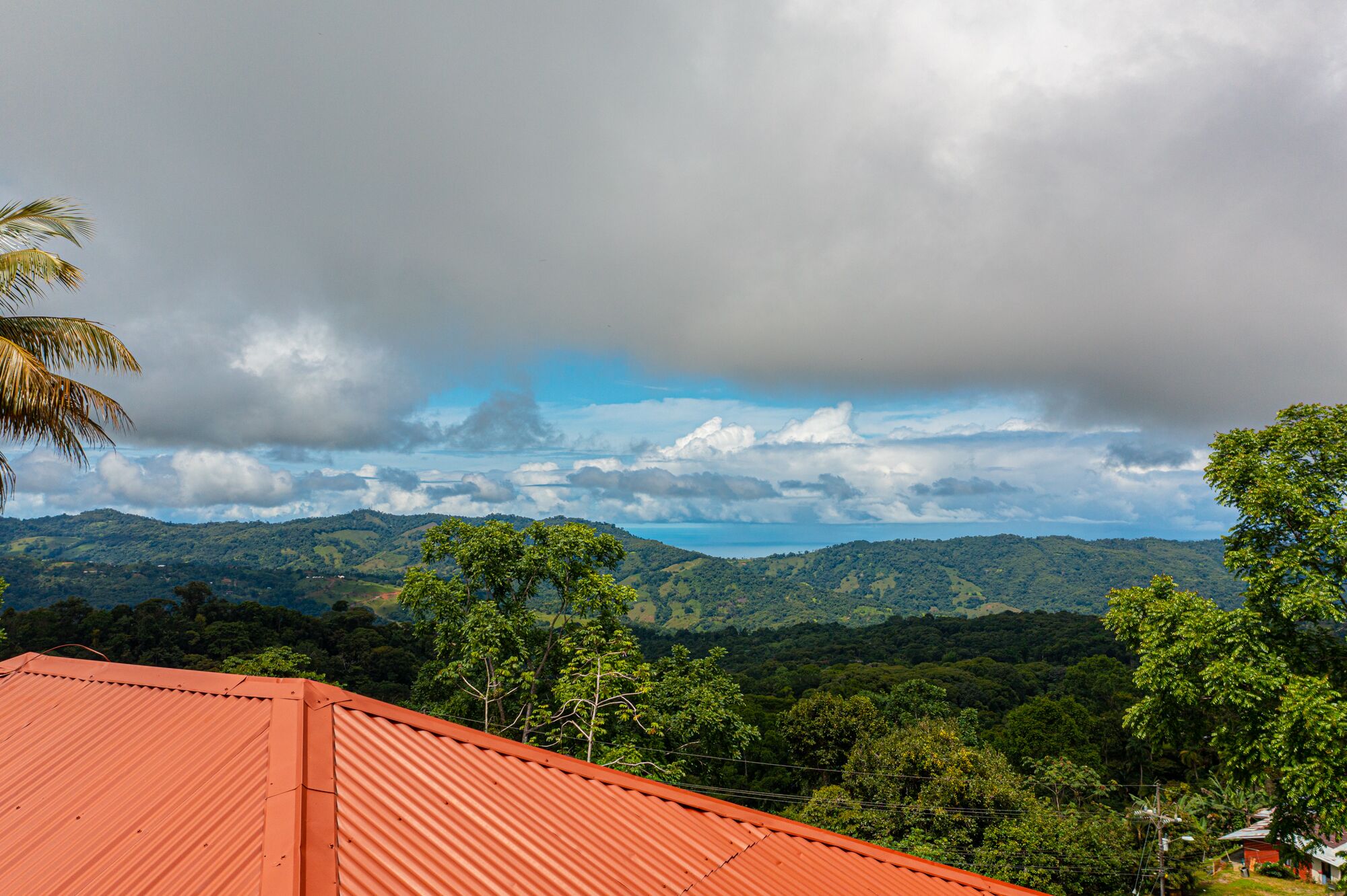Vista de un paisaje montañoso con un edificio de techo rojo al frente.