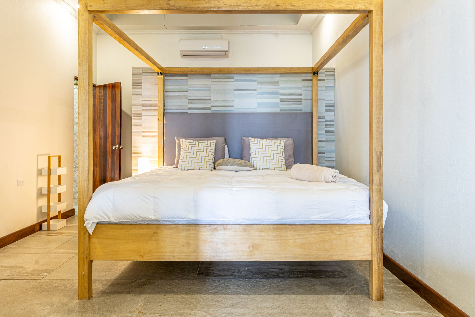 Un lit à baldaquin avec une structure en bois et une tête de lit à motifs rayés.