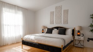 A bedroom with a bed, two bedside tables, and a nightstand.