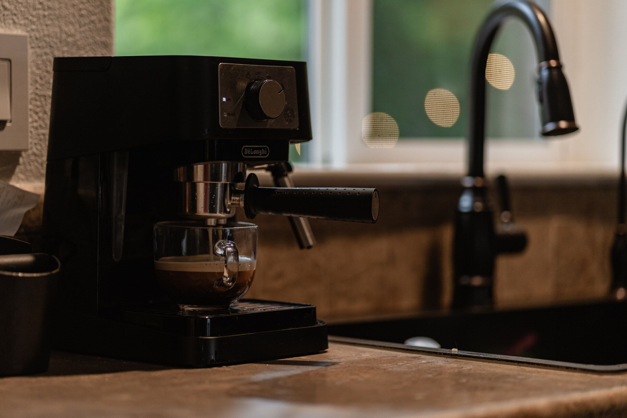 A coffee machine with a cup of coffee on a kitchen counter.