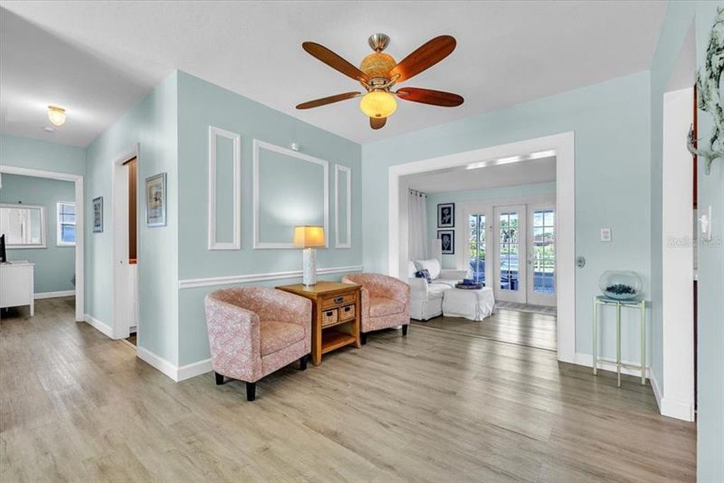 A spacious living room with a ceiling fan, a wooden coffee table, and two armchairs.