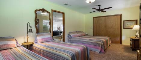 A room with three beds, a ceiling fan, and a large mirror.