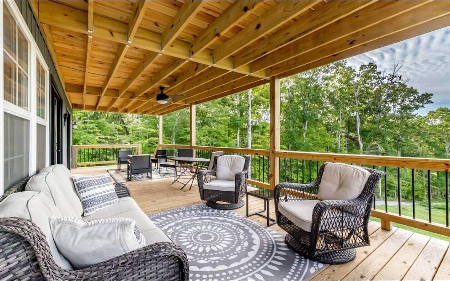 Une terrasse extérieure couverte, aménagée avec des meubles en osier, une table à manger et des chaises.