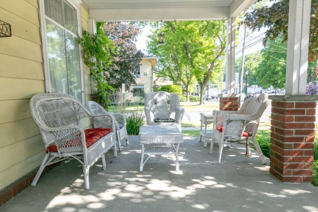 A covered porch with wicker furniture and a brick pillar.