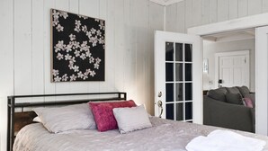 Et soveværelse med en seng, en dør og en væg med et blomsterkunstværk.