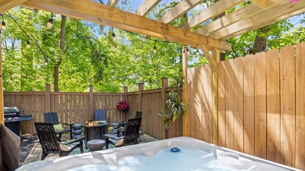 A hot tub under a wooden pergola with a wooden fence and greenery in the background. - Walk to Ithaca Commons+Trails! (Ithaca)