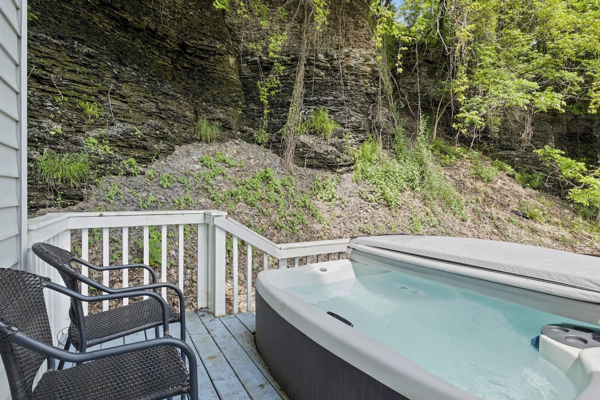 A hot tub on a wooden deck with a view of a rocky cliff and trees.